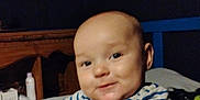 Kasson is registered to the contest to win money with this photo: baby, child, smiling, striped_shirt, monkey, yellow_excavator, indoor, furniture, blanket, wood, cute, portrait, infant, happy, person, toddler, clothing, face, seated, playful