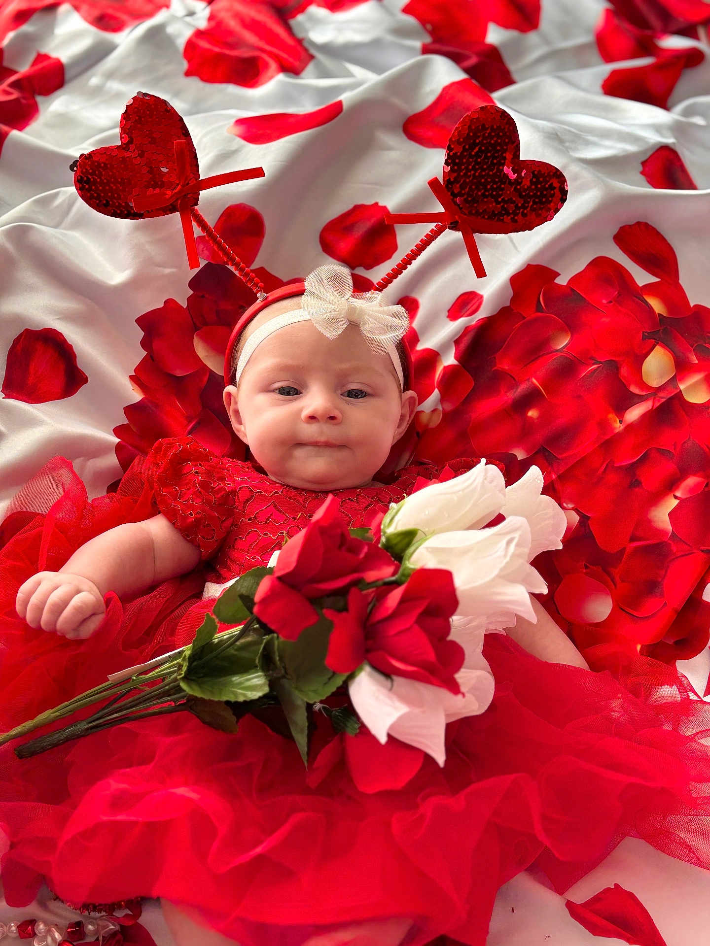 Mckenna joined the competition — help win amazing prizes! baby, infant, child, red_dress, headband, heart_antenna, bouquet, roses, rose_petals, fabric, bed, portrait, tulle, valentine_theme, red, white, cute, laying, close_up, adorable