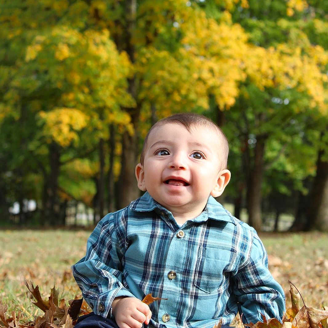 Joshua joined the competition — help win amazing prizes! clothing, face, grass, grove, head, land, leaf, nature, outdoors, pants, park, person, photography, plant, portrait, shirt, sitting, tree, vegetation, woodland