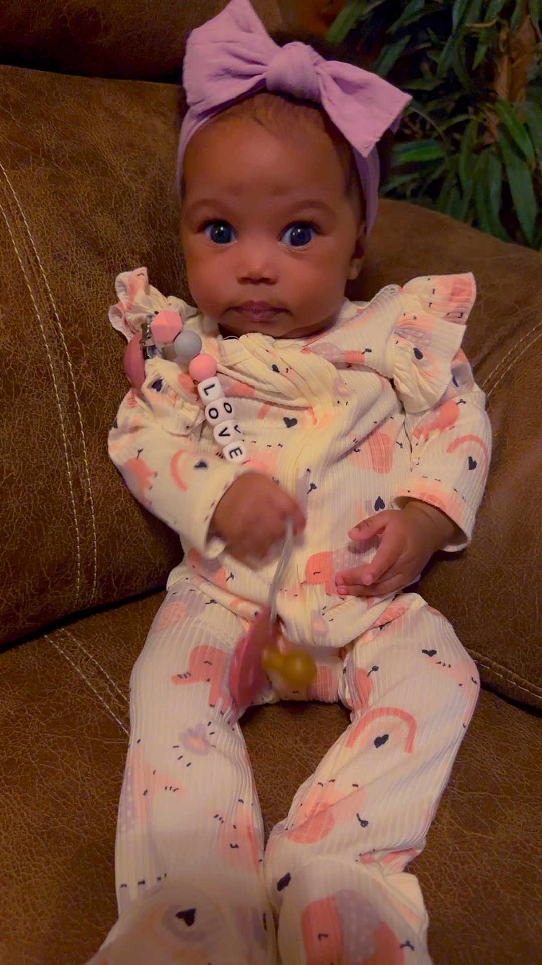 Love is registered to the contest to win money with this photo: baby, bow, child, clothing, couch, cute, hand, headband, heart, indoors, infant, leather, love, onesie, pacifier, person, portrait, rainbow, seated, toy