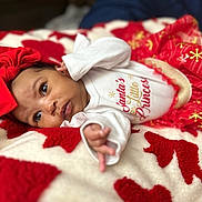 Love joined the competition — help win amazing prizes! baby, infant, red_bow, white_onesie, red_skirt, blanket, holiday_theme, cute, portrait, face, hand, lying_down, cozy, soft_texture, christmas, child, young, small, adorable, festive