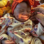 Love joined the competition — help win amazing prizes! baby, smiling, dimple, headband, orange, pajamas, floral_pattern, blanket, fall_theme, pumpkin, pinecone, hand, cozy, infant, cute, sleepy, indoor, portrait, child, soft_lighting