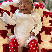 Love is registered to the contest to win money with this photo: baby, infant, smiling, white_clothing, red_polka_dot, leggings, headband, bow, blanket, patterned, cozy, happy, cute, indoors, portrait, child, person, soft, warm, resting