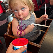 Gracie joined the competition — help win amazing prizes! toddler, child, drinking, straw, cup, high_chair, indoor, blonde_hair, blue_eyes, casual_dining, wooden_chair, curious, holding, gray_shirt, hand, face, person, table, red, plastic