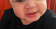 Amaris is registered to the contest to win money with this photo: baby, child, smiling, face, person, cute, toddler, black_shirt, colorful, flower_print, indoors, orange_background, happy, portrait, close_up, skin, eyelashes, cheeks, head, expression