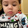 Amaris is registered to the contest to win money with this photo: toddler, child, face, curly_hair, shirt, superhero, colorful, expression, indoors, portrait, clothing, text, casual_wear, young_child, cute, person, closeup, skin, sleeve, young