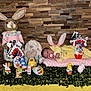 baby, bunny_ears, stuffed_animals, chocolate, kinder_surprise, pink_blanket, yellow_pajamas, table, greenery, wooden_wall, easter_eggs, toy_bunny, pacifier, decorations, indoor, holiday, child, soft_toys, cute, celebration