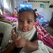 Kaizen is registered to the contest to win money with this photo: baby, infant, child, bed, blanket, pillow, room, window, curtains, television, furniture, calendar, bib, person, indoor, clothing, face, hair, hand, expression