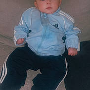 Maël a rejoint le concours — aidez-le/la à gagner de superbes lots ! baby, child, infant, couch, clothing, tracksuit, blue, black, sitting, face, person, indoor, furniture, cushion, portrait, young_child, expression, casual, comfortable, home