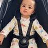 baby, bird_pattern, black_fabric, buckle, car_seat, child, curly_hair, cute, earring, harness, indoor, large_eyes, neutral_expression, onesie, pale_skin, portrait, seated, stroller, toddler, window
