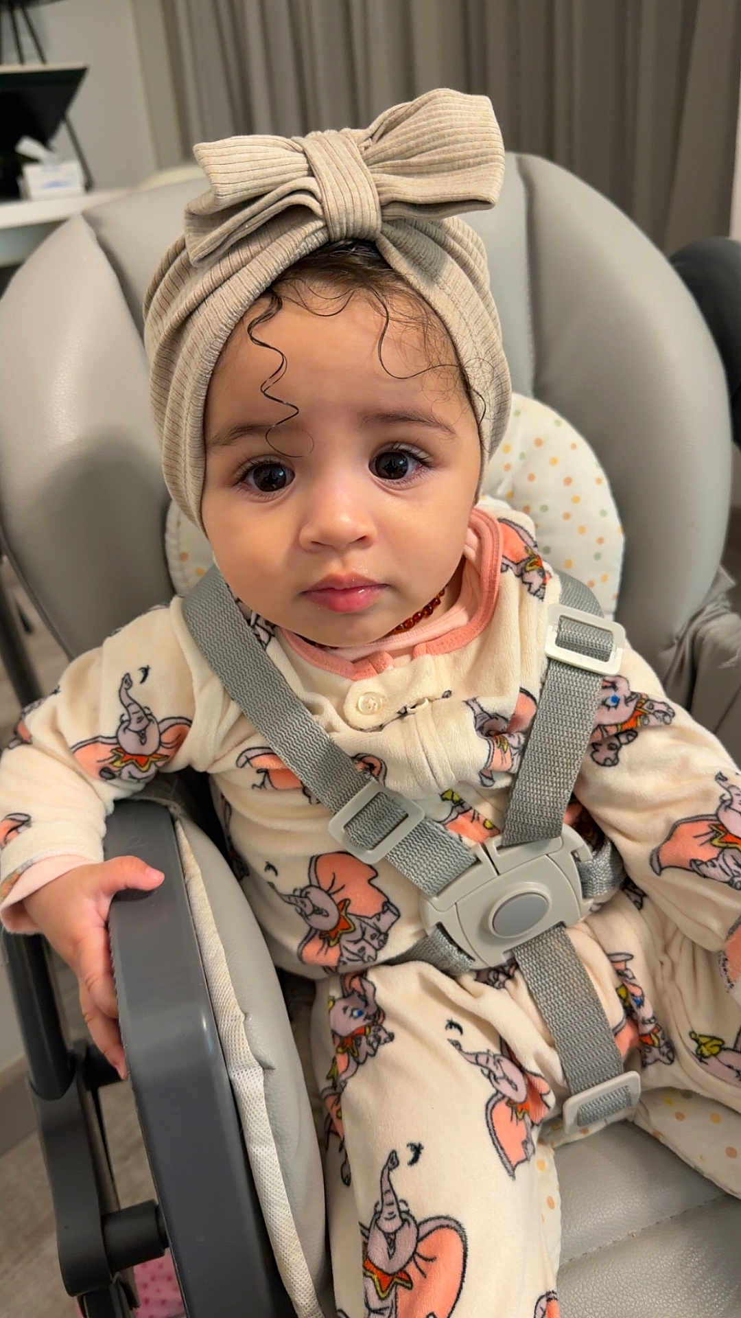 Julia a rejoint le concours — aidez-le/la à gagner de superbes lots ! baby, child, infant, highchair, headwrap, bow_headband, pajamas, elephant_print, harness, buckle, big_eyes, curly_hair, hand, seat, indoor, portrait, clothing, adorable, sitting, neutral_expression
