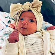 Aria is registered to the contest to win money with this photo: newborn, baby, infant, child, portrait, close_up, face, eyes, bow, headband, clothing, striped_outfit, blanket, bed, indoors, cozy, lying_down, looking_at_camera, cute, photography