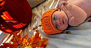 Eriel joined the competition — help win amazing prizes! baby, infant, child, portrait, lying_down, orange_hat, knitted_hat, autumn, fall, pumpkin, leaves, bed, blanket, indoor, sunlight, shadows, cozy, seasonal, sleeping, closeup