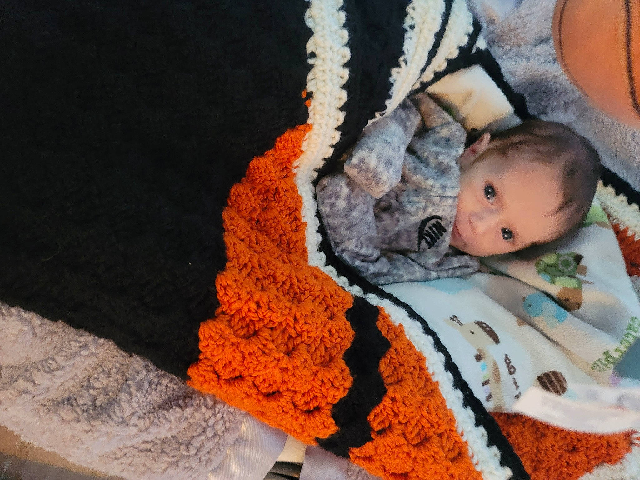 Lyrik is registered to the contest to win money with this photo: art, baby, baby_products, baby_toddler_clothing, cap, child, comfort, craft, human_body, knit_cap, linens, orange, pattern, person, sitting, sleeve, textile, toddler, wood, wool