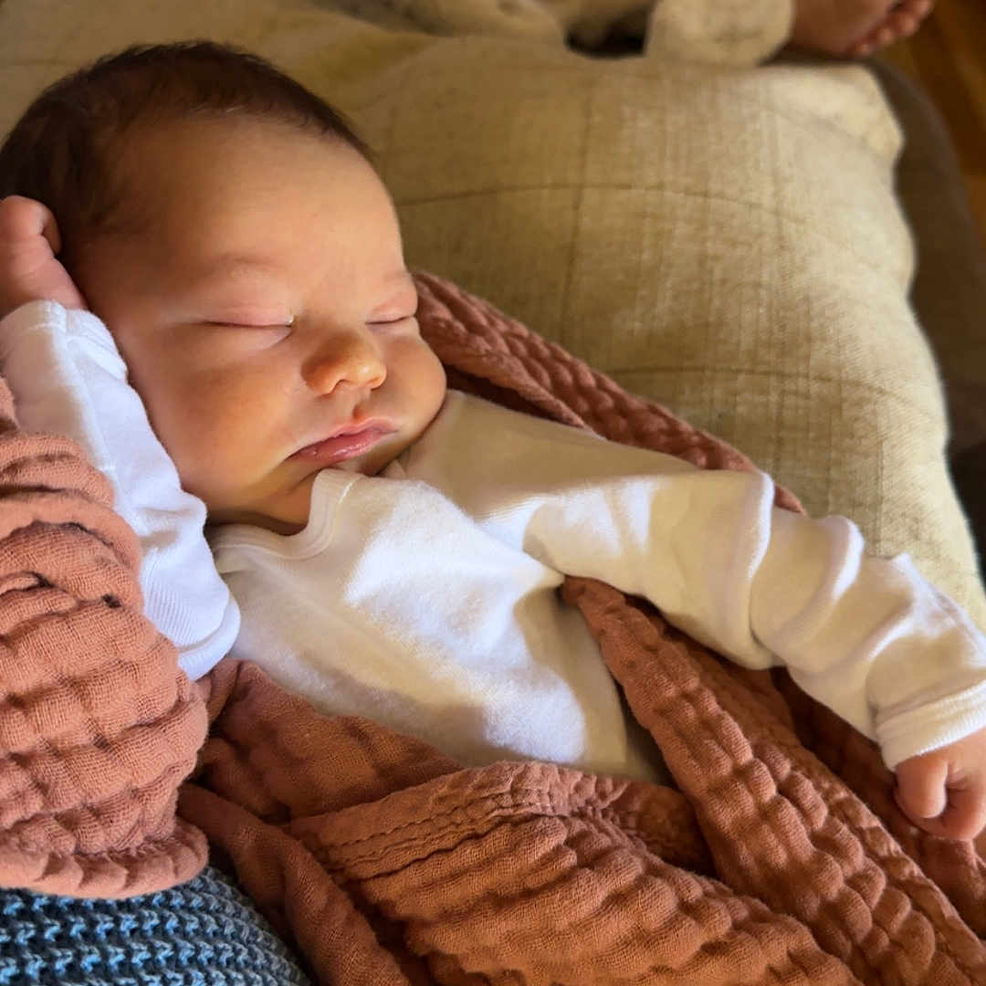 Dawson is registered to the contest to win money with this photo: baby, sleeping, blanket, couch, infant, cozy, rest, child, indoors, soft, texture, warm_colors, white_clothing, peaceful, relaxing, portrait, young_child, home, comfort, nap