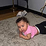 baby, infant, carpet, pink_shirt, black_pants, floor, indoor, television, cable, curious, child, person, room, furniture, lamp, wall, power_outlet, technology, relaxing, casual