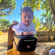 Lorenzo participe au concours pour gagner de l'argent avec cette photo : baby, child, scooter, piaggio, outdoor, sunny, greenery, plants, tree, seat, hands, face, expression, daylight, vehicle, transportation, casual, nature, portrait, person