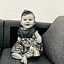 baby, child, smile, sitting, dress, couch, furniture, happy, face, foot, patterned_clothing, indoors, portrait, cute, monochrome, infant, person, young_child, home, texture