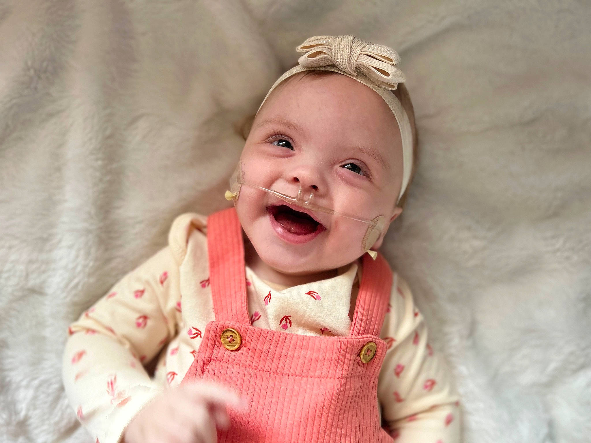 Laila is registered to the contest to win money with this photo: baby, baby_toddler_clothing, cheek, collar, comfort, ear, eyelash, face, fashion_accessory, happy, iris, lip, neck, pattern, person, pink, skin, sleeve, smile, textile