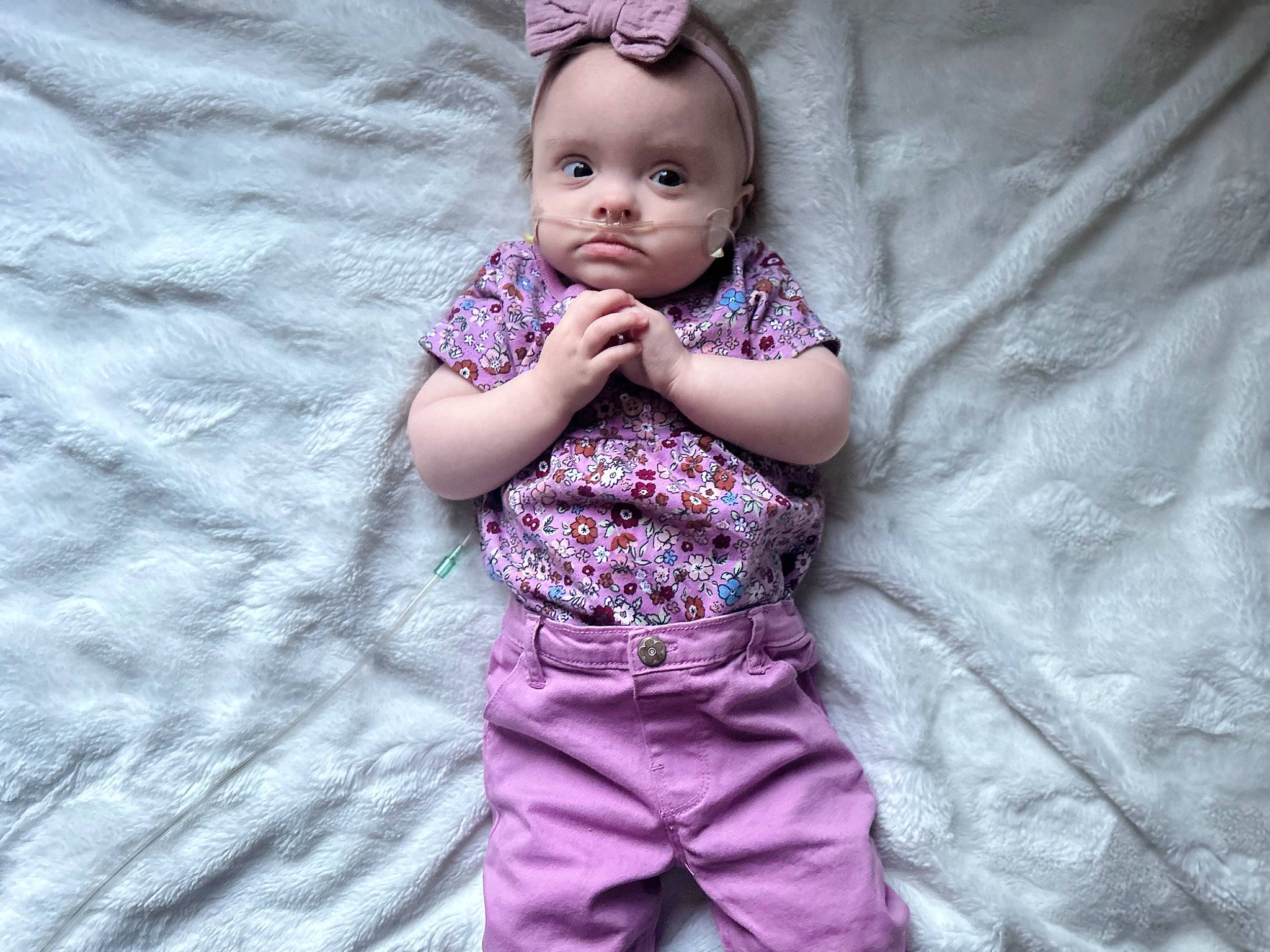 Laila is registered to the contest to win money with this photo: arm, baby, baby_toddler_clothing, child, eye, face, facial_expression, gesture, grey, magenta, outerwear, pattern, person, pink, purple, skin, sleeve, t_shirt, textile, toddler