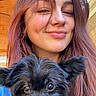 Olive joined the competition — help win amazing prizes! woman, dog, puppy, smile, face, hair, pet, black_dog, portrait, indoor, wood_ceiling, happy, cute, young_adult, long_hair, casual, holding, looking_at_camera, natural_light, closeup