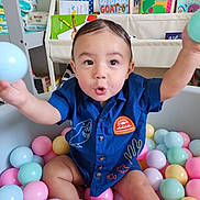 Ace is registered to the contest to win money with this photo: toddler, child, ball_pit, colorful_balls, blue_shirt, embroidery, playful_expression, indoor, bookshelf, children_books, baby_supplies, diapers, toy, happy, reaching_out, playroom, cute, portrait, person, smiling