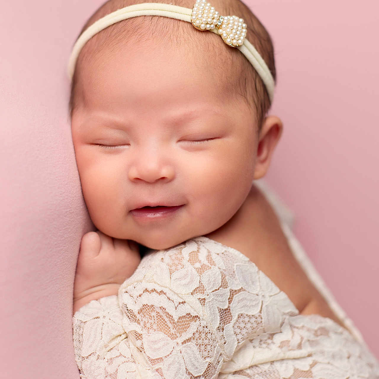 Vivian is registered to the contest to win money with this photo: baby, child, close_up, cute, delicate, face, hand, headband, indoors, infant, lace_outfit, newborn, peaceful, pearl_bow, pink_background, portrait, resting, skin, sleeping, soft_texture