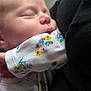 baby, sleeping, infant, face, closeup, child, floral_pattern, clothing, peaceful, soft_light, portrait, newborn, cute, resting, skin, hand, person, fabric, comfort, warm