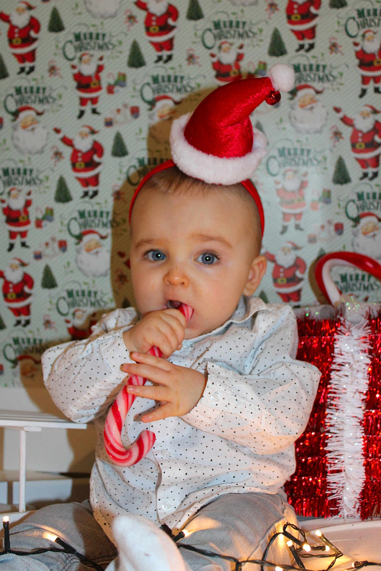 Mylann participe au concours pour gagner de l'argent avec cette photo : baby, child, candy_cane, christmas_hat, holiday_lights, gift_box, festive, santa, wrapping_paper, polka_dot_shirt, cute, indoors, celebration, holiday, smiling, sitting, decorations, red, white, toddler