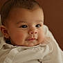 baby, infant, face, closeup, cheeks, eyes, smile, portrait, white_shirt, buttons, ear, head, soft_light, brown_background, cozy, skin, eyelashes, seated, cute, child