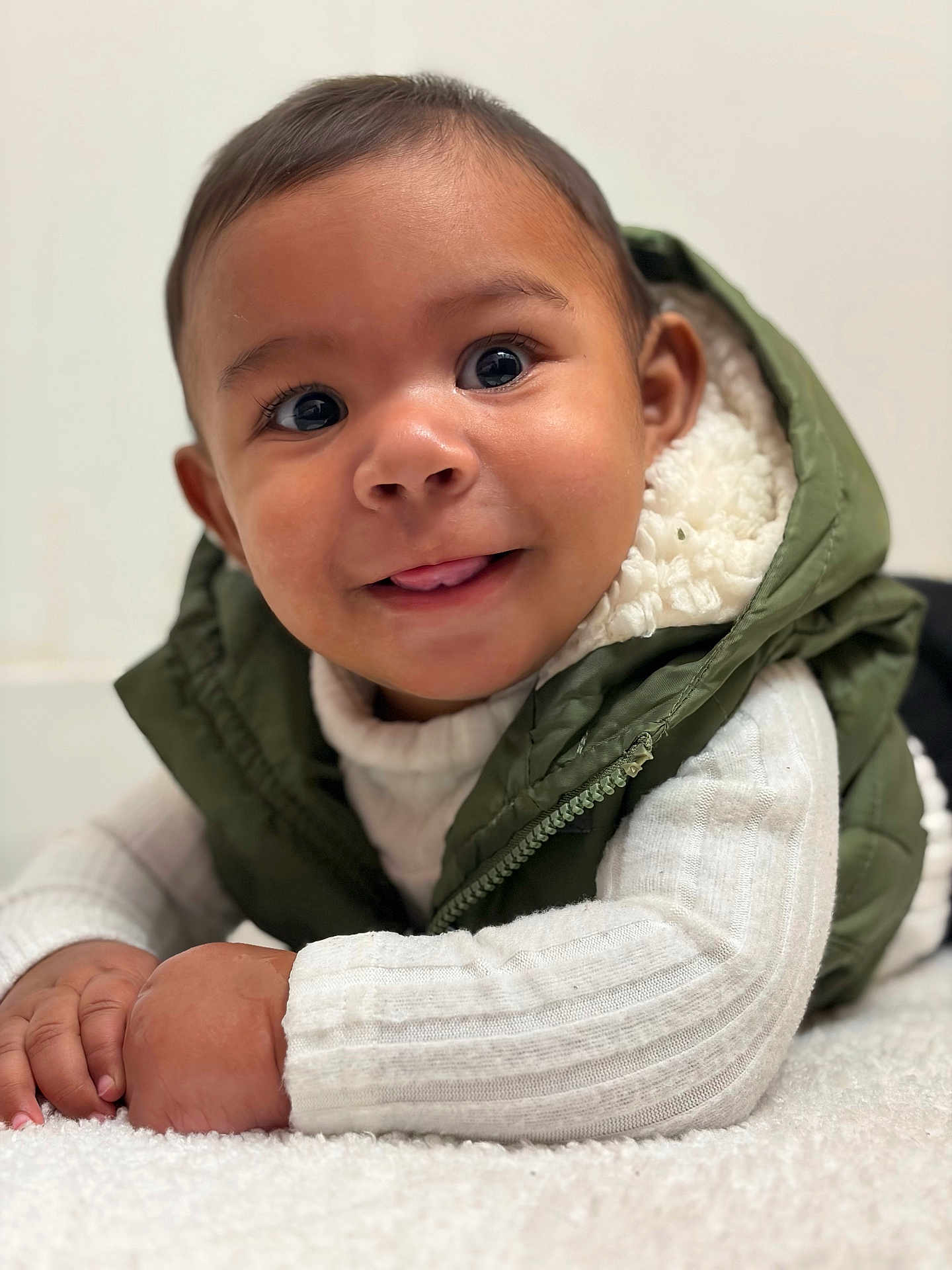 Noah Jeuniel joined the competition — help win amazing prizes! baby, child, face, smile, tongue, eyes, vest, green, white_sweater, hand, crawling, indoor, cute, portrait, infant, warm_clothing, fluffy_surface, closeup, happy, skin