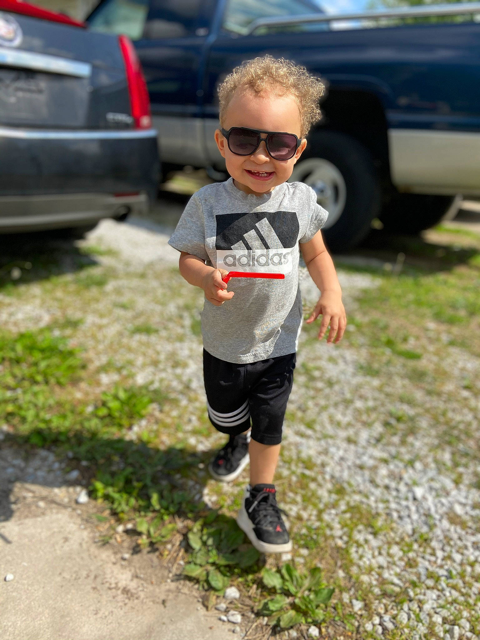 Jamari is registered to the contest to win money with this photo: asphalt, automotive_exterior, bumper, car, cool, eyewear, footwear, glasses, goggles, grass, joy, land_vehicle, leisure, person, plant, recreation, shorts, street_fashion, sunglasses, t_shirt