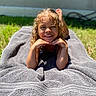 child, smiling, curly_hair, towel, outdoor, sunlight, grass, happy, portrait, young, relaxing, person, casual, daylight, skin, head, face, barefoot, nature, leisure
