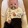 Jace is registered to the contest to win money with this photo: baby, infant, pacifier, clothing, black_pants, cream_shirt, bat_prints, face, eyes, hand, cushion, fabric, comfort, indoor, portrait, cute, child, lying_down, looking, skin