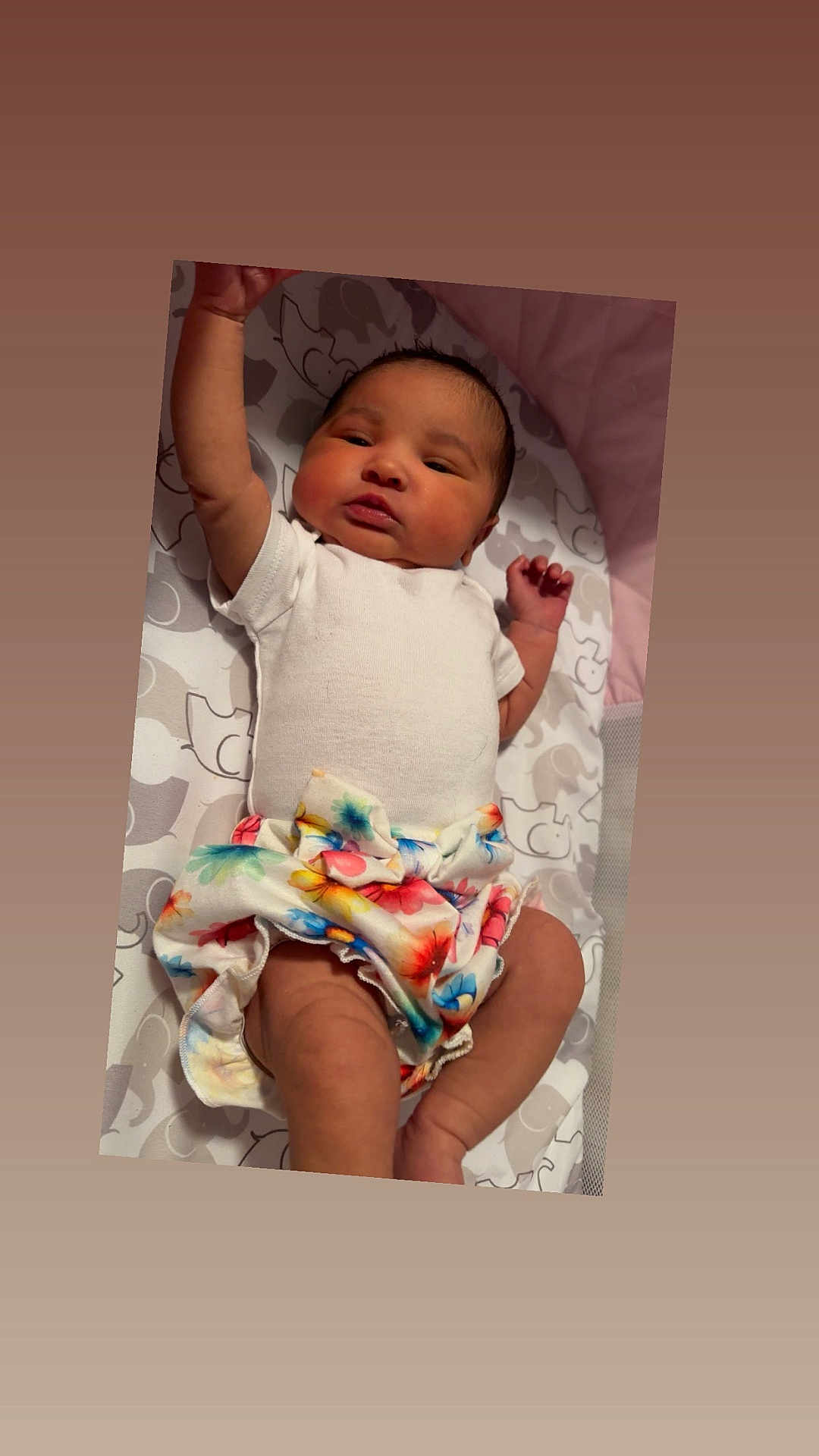 Ivie joined the competition — help win amazing prizes! baby, infant, child, onesie, skirt, floral_pattern, blanket, lying_down, arm_raised, cute, newborn, face, head, skin, person, indoors, soft_lighting, pattern, colorful, clothing