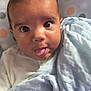 Shyro is registered to the contest to win money with this photo: baby, child, tongue_out, blanket, polka_dot, colorful_background, wide_eyes, cute, infant, face, expression, soft_fabric, seated, indoors, close_up, person, portrait, playful, curious, young