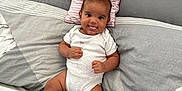 Shyro is registered to the contest to win money with this photo: baby, infant, tongue_out, onesie, pillow, bed, blanket, smile, cheeky, cute, lying_down, cozy, soft, indoors, headboard, striped, fabric, person, child, happy