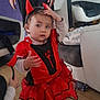 Sonaly a rejoint le concours — aidez-le/la à gagner de superbes lots ! toddler, child, costume, devil, red_dress, horns, indoor, living_room, adult, person, floor, furniture, sofa, television, curious, standing, hand, clothing, headband, cute