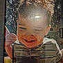child, smiling, curly_hair, spoon, framed_photo, reflection, glare, portrait, indoor, happy, young, face, clothing, striped_shirt, person, close_up, photograph, window_reflection, candid, joy