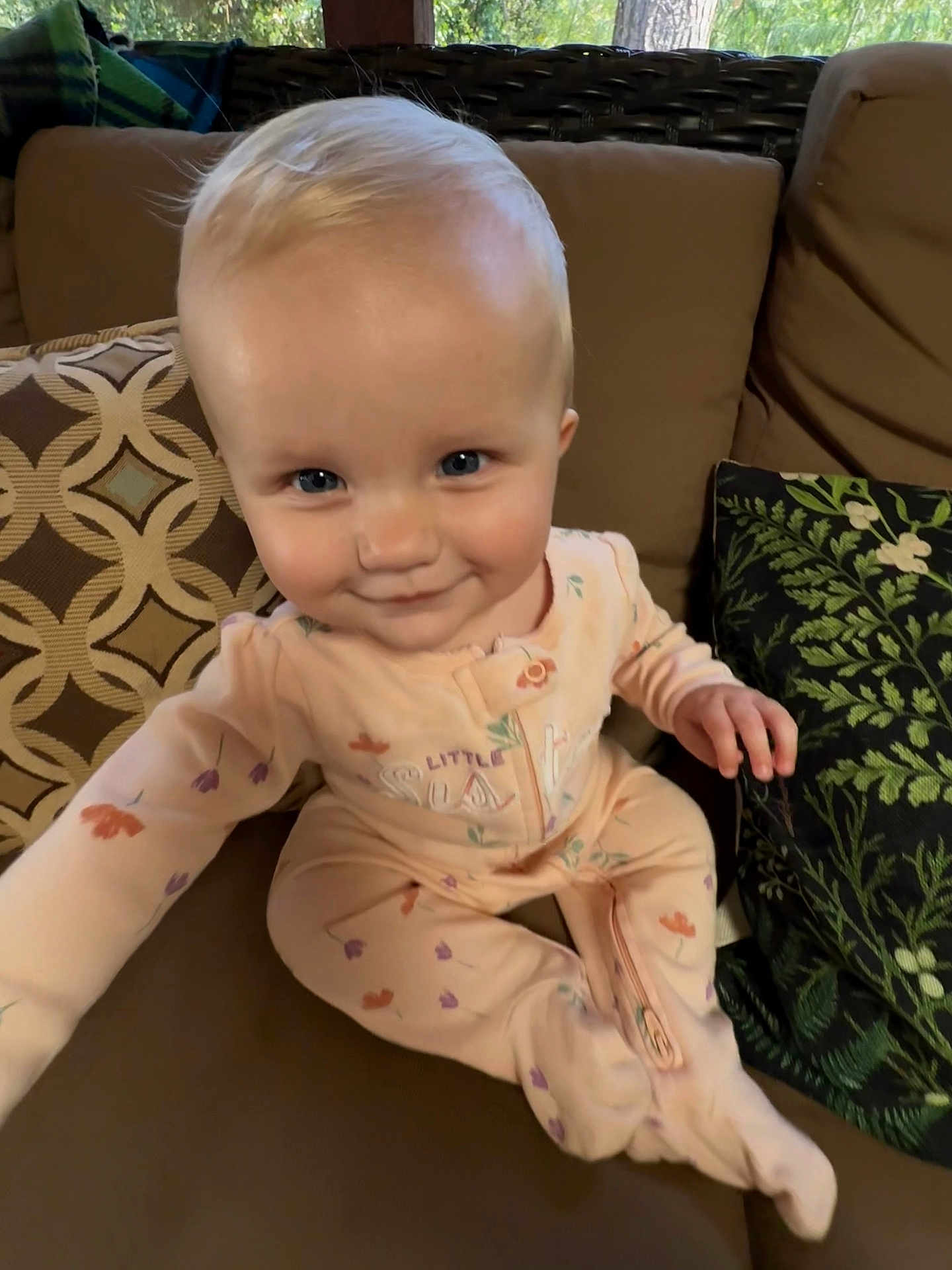 Lyla is registered to the contest to win money with this photo: baby, child, infant, couch, cushion, blue_eyes, blonde_hair, onesie, sitting, indoor, pattern, plush, smile, curious, hand, footed_pajamas, comfort, home, portrait, young