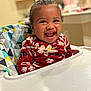 toddler, child, smiling, high_chair, red_clothing, floral_pattern, indoor, kitchen, happy, person, face, baby, seat, cute, cheerful, young_child, home, laughter, colorful, portrait