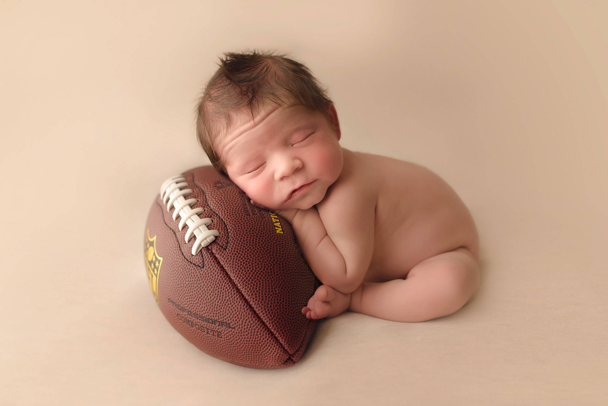 Grey is registered to the contest to win money with this photo: american_football, arm, baby, ball, ball_game, comfort, elbow, foot, football, gesture, happy, human_body, knee, person, playing_sports, sports, sports_equipment, sports_toy, team_sport, toddler
