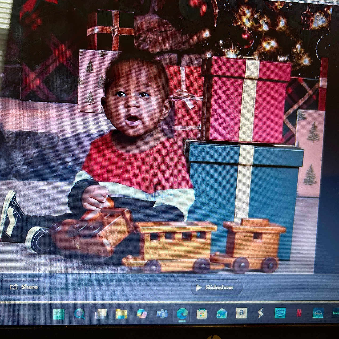 Naair joined the competition — help win amazing prizes! toddler, child, toy_train, wooden_toy, christmas_presents, gift_boxes, christmas_tree, holiday, red_sweater, floor, indoor, smiling, happy, festive, decorations, play, cute, portrait, sitting, holiday_season
