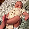 Jasper is registered to the contest to win money with this photo: baby, infant, smile, face, foot, blanket, bedspread, buttoned_shirt, diaper, lying_down, indoor, child, cute, happy, person, soft_texture, pattern, home, relaxed, young