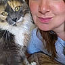 Bell is registered to the contest to win money with this photo: cat, woman, selfie, portrait, calico_cat, fluffy, whiskers, green_eyes, smiling, face, human, pet, indoors, close_up, cuddling, blue_shirt, brown_hair, blanket, home, photography