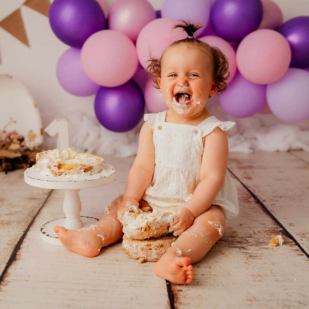 Romy participe au concours pour gagner de l'argent avec cette photo : baby, birthday, cake, celebration, child, cute, decorations, first_birthday, floor, food, fun, happy, messy, party, pink_balloons, portrait, purple_balloons, sitting, smiling, white_dress