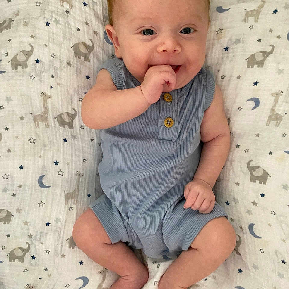 Micah joined the competition — help win amazing prizes! baby, biting, blanket, bodypart, clothing, eating, face, finger, food, hand, happy, head, newborn, pants, person, photography, portrait, sitting, sleeve, yawning