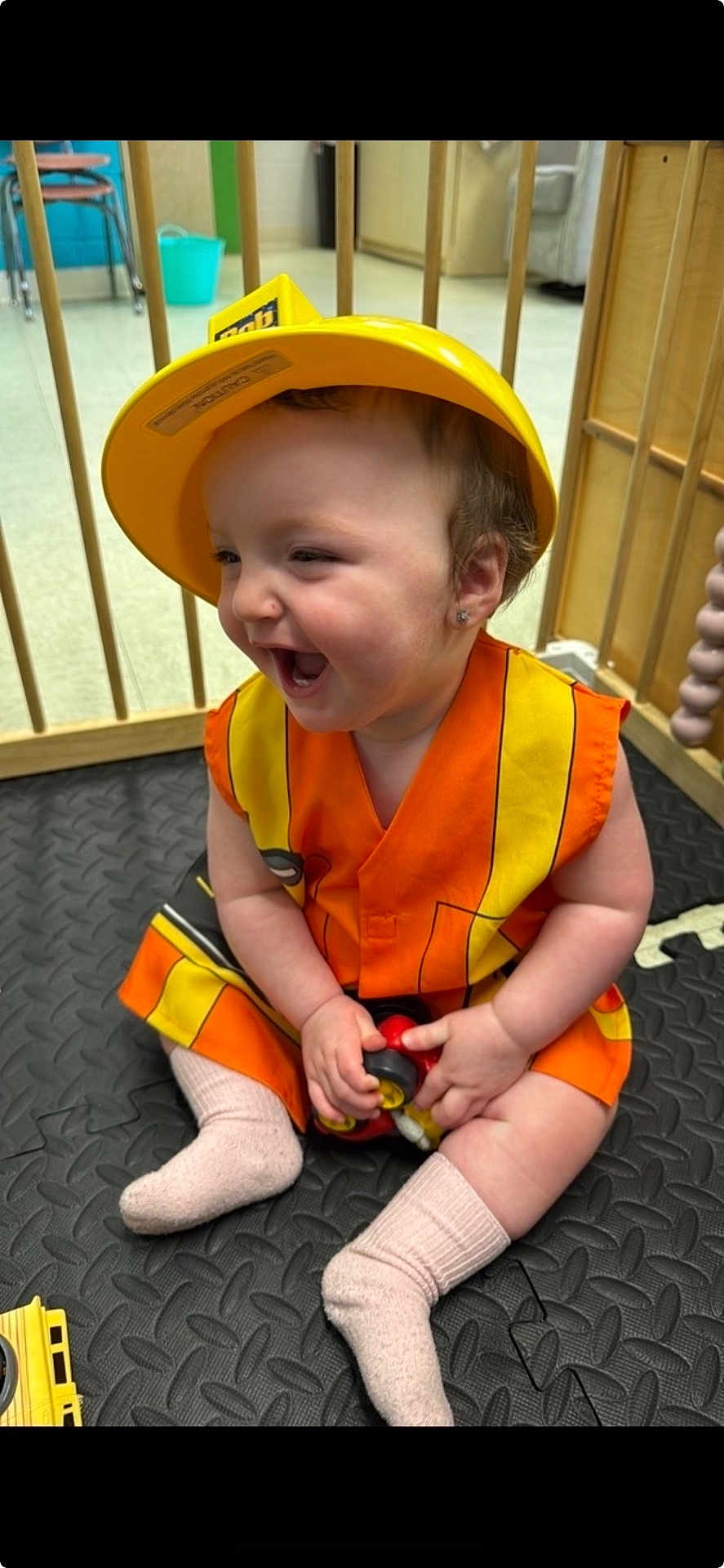 Navaya joined the competition — help win amazing prizes! toddler, child, smiling, hard_hat, construction_vest, toy_car, socks, indoor, play_area, floor_mat, wooden_bars, happy, cute, playful, baby, earrings, seat, daycare, colorful, laughing