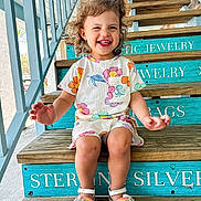 Callie is registered to the contest to win money with this photo: architecture, building, child, clothing, face, female, footwear, happy, head, house, housing, person, photography, portrait, sandal, shoe, shorts, sitting, staircase, wood