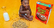 Zayyvon is registered to the contest to win money with this photo: baby, toddler, child, smiling, laughing, cereal, bowl, milk, glass_bottle, food, breakfast, yellow_background, cereal_box, reese's_puffs, happy, sitting, indoors, cute, playful, person